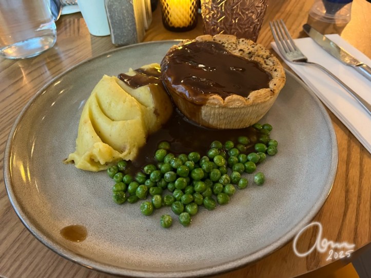 Plate with traditional British steak pie, mashed potatoes and peas